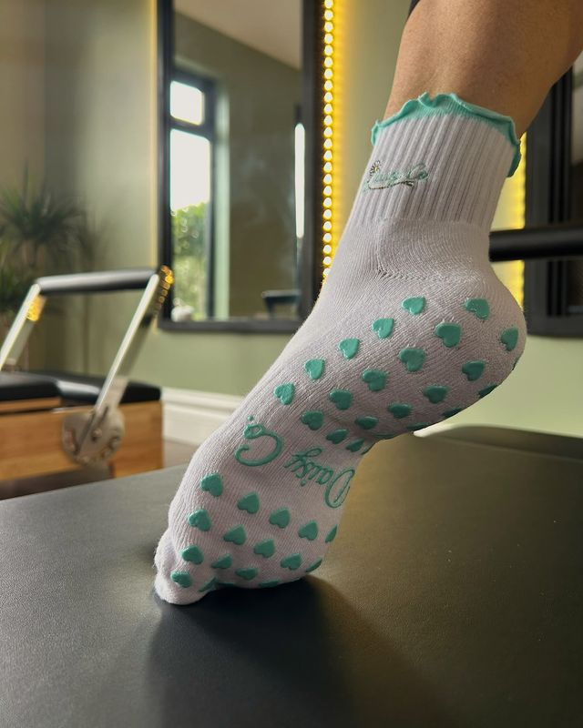 The silicone heart grip on the sole of a Sea Mist sock, on a reformer
